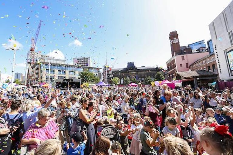 Picture of a group of people celebrating at an event in Millenium Square, Leeds
